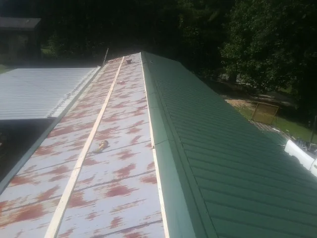 Old rusted panels beside newly installed green metal roofing — Wind Damage Roof Repair by Roofing Brothers in Algodones