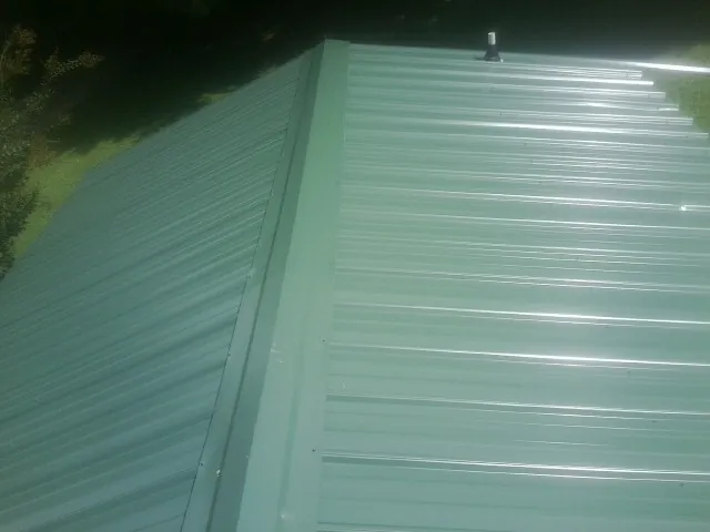 New green metal panels meeting at the ridge of a roof — Flat Roof Repair work by our crew in Algodones