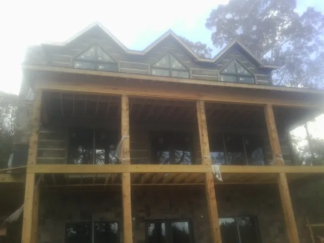 Dormers and porch framing on a large log home under construction — Roof Coating work by our crew in Algodones