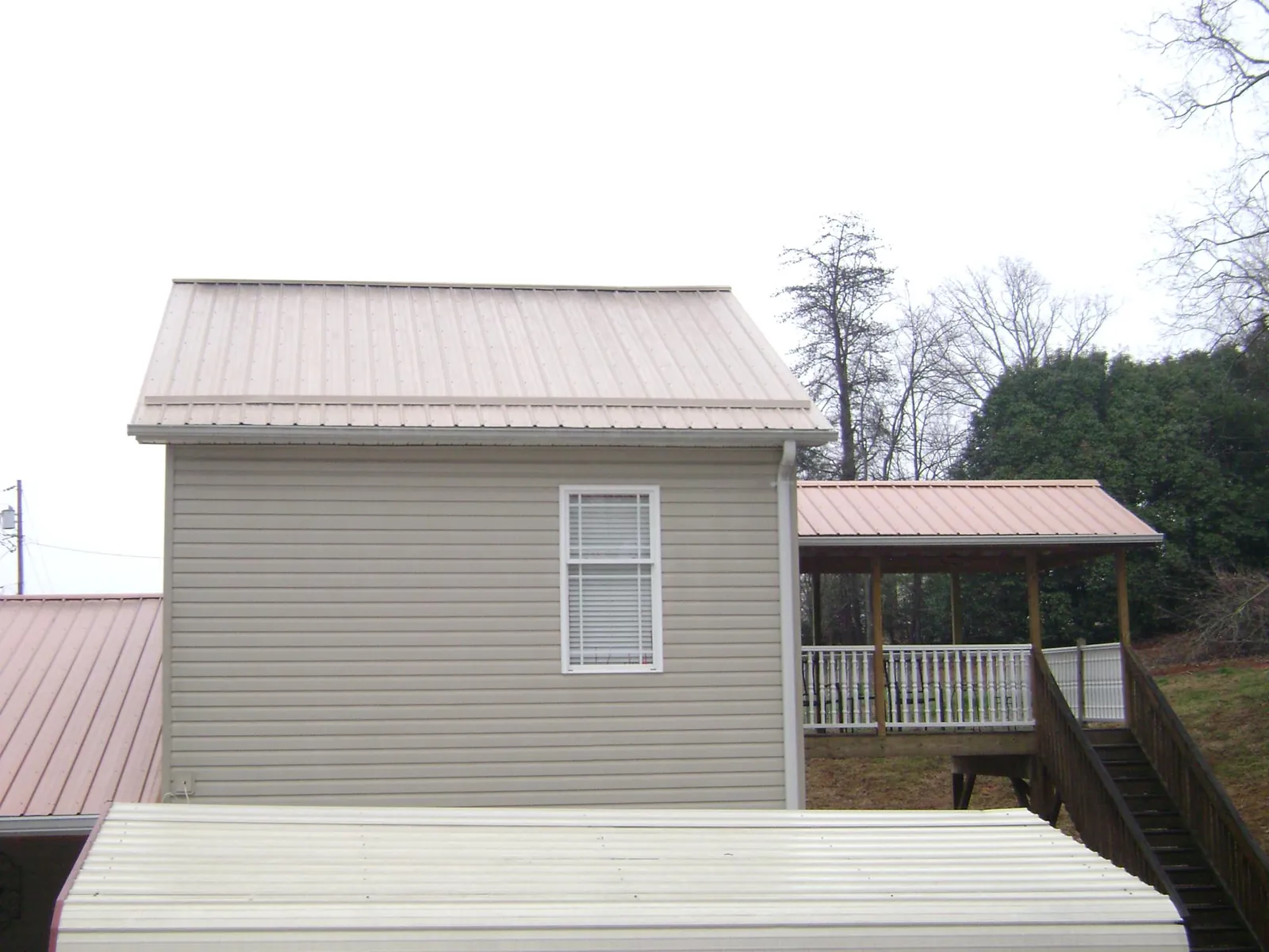 Tan metal roofs on a two story addition and attached porch, from a Roof Replacement job in Algodones