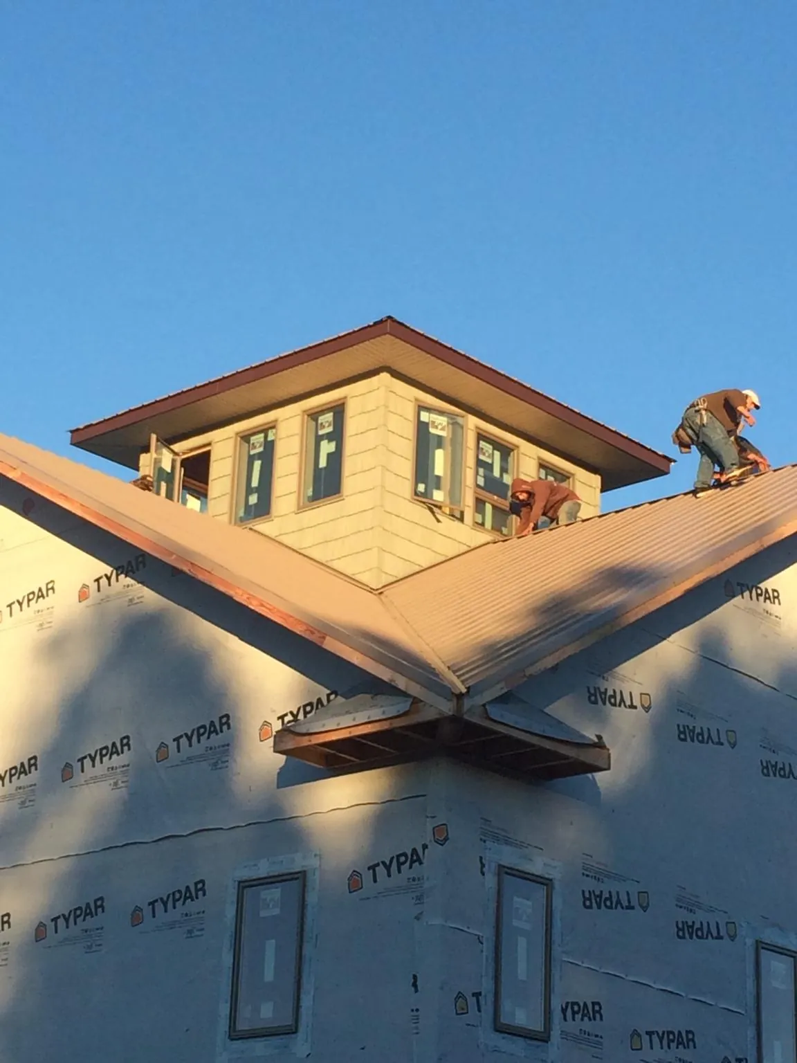 Roofers working around a rooftop cupola on a new metal roof at sunset — Roof Waterproofing in Algodones by Roofing Brothers